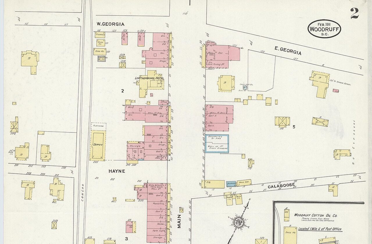 Hand-colored February 1911 Sanborn fire insurance map of downtown Woodruff: Main Street crossed by West and East Georgia Street, with the Leatherwood Hotel, the depot beside the railroad, and the map’s “Feb. 1911 Woodruff S.C.” seal.
